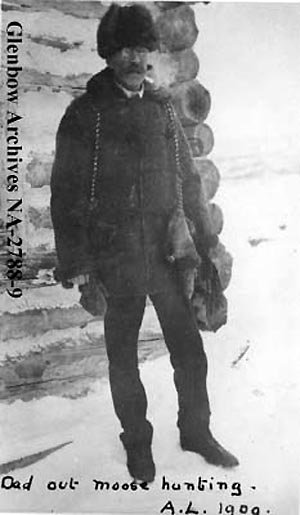 Dressed for winter moose hunt in fur jacket, hat and mitts. 1909